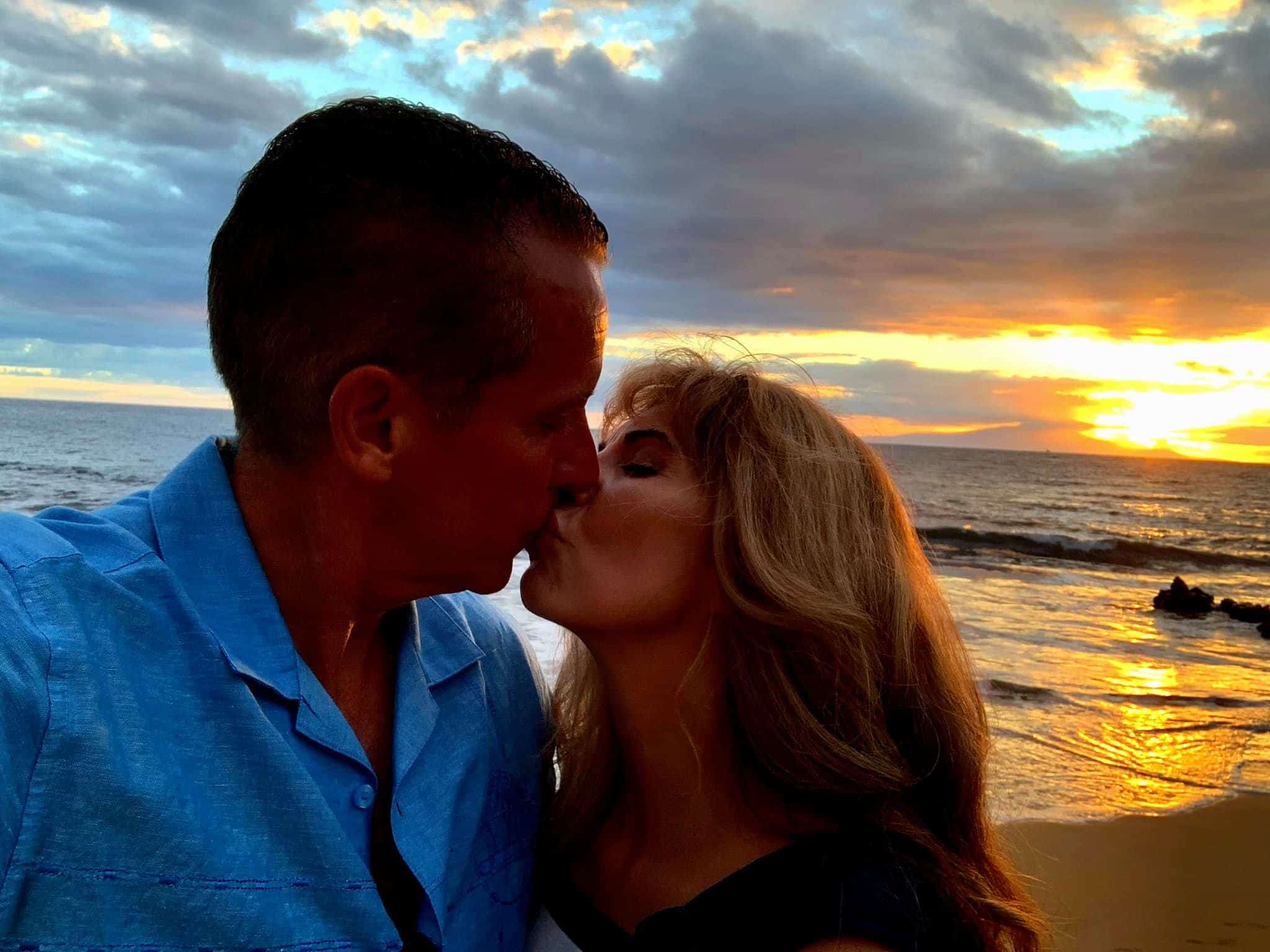 A man and woman keeping the flame alive as they kiss on the beach at sunset