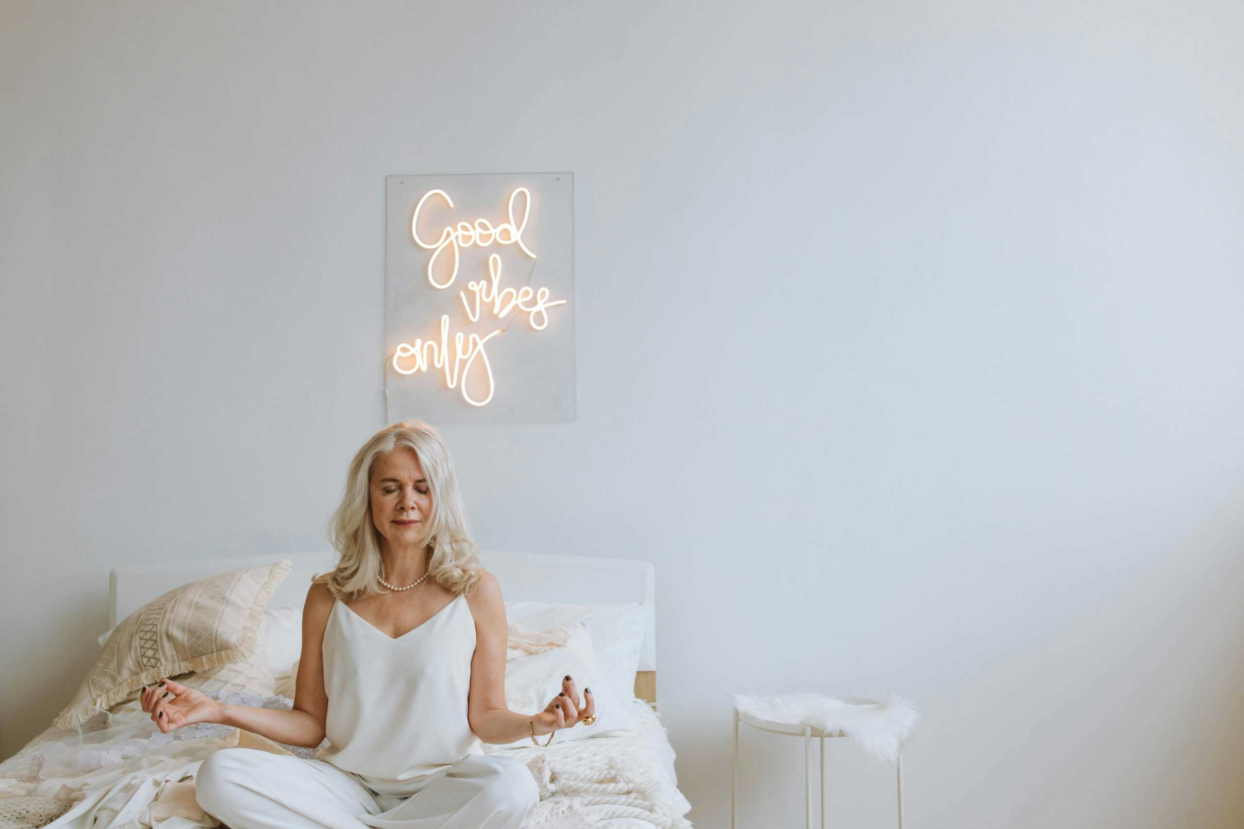 A woman embracing the concept of lifelong learning while meditating on a bed with a good night sign.