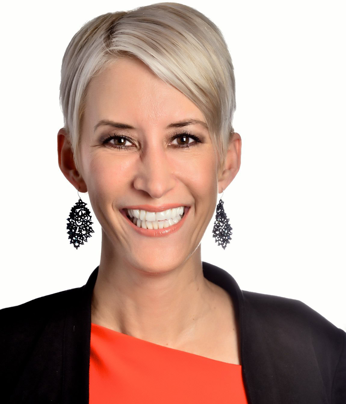 Jennifer K Hill, a woman with short blonde hair and large black earrings, smiling in a red top against a white background.
