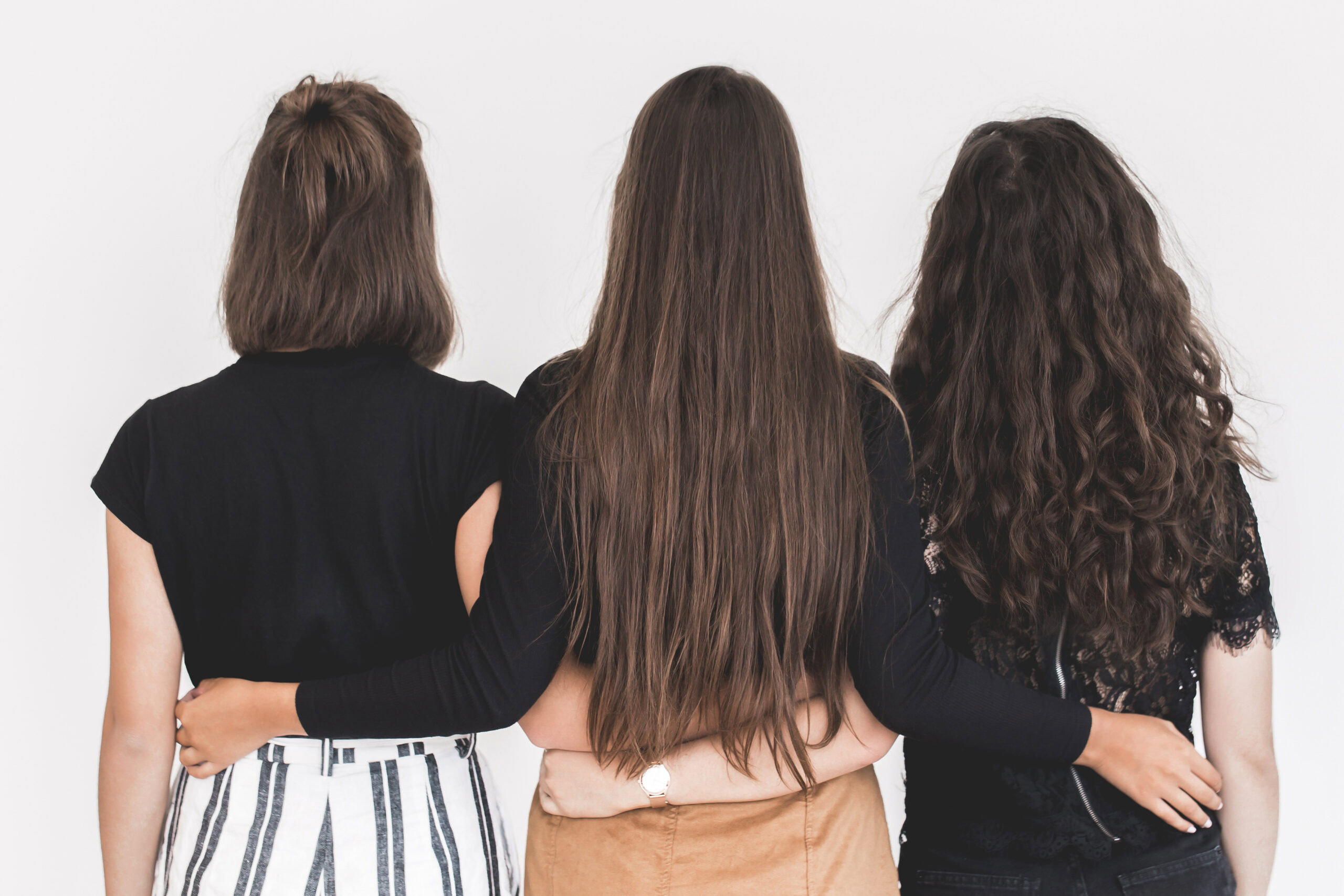 Three people, including Janet Zavala, stand with their backs to the camera, arms linked around each other's waists. Their unity symbolizes overcoming self-sabotage and embracing collective strength.