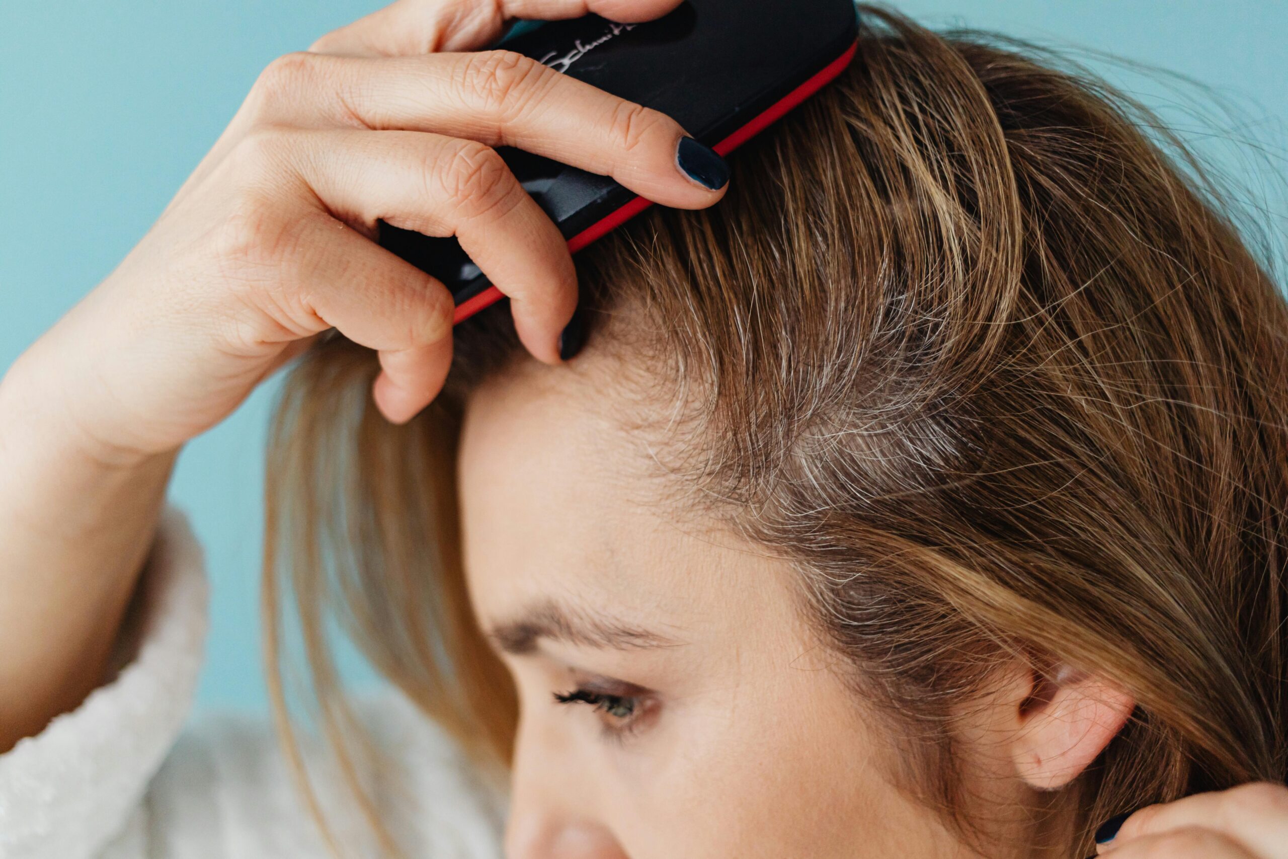 A person brushes their hair, focusing on the roots, mindful of hair loss after menopause.