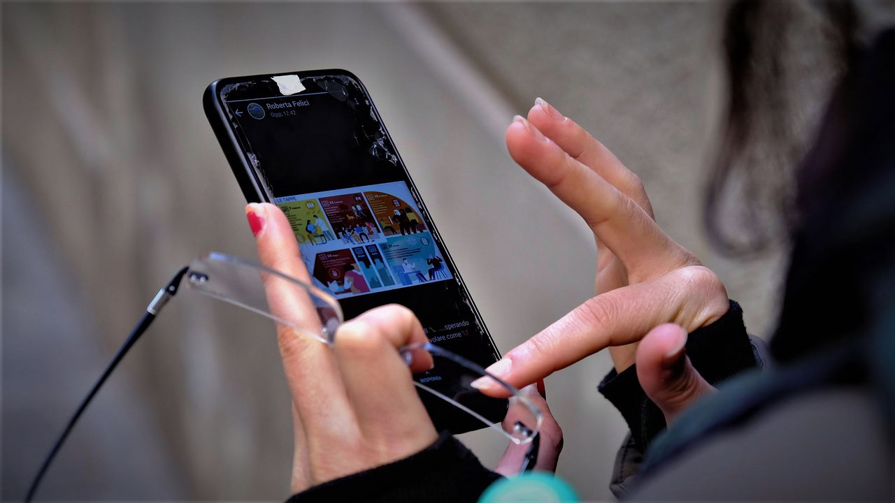 A person, stressed over social media comparisons, holds a cracked smartphone while interacting with an app. In the other hand, a pair of glasses rests as if seeking clarity amidst the digital chaos.