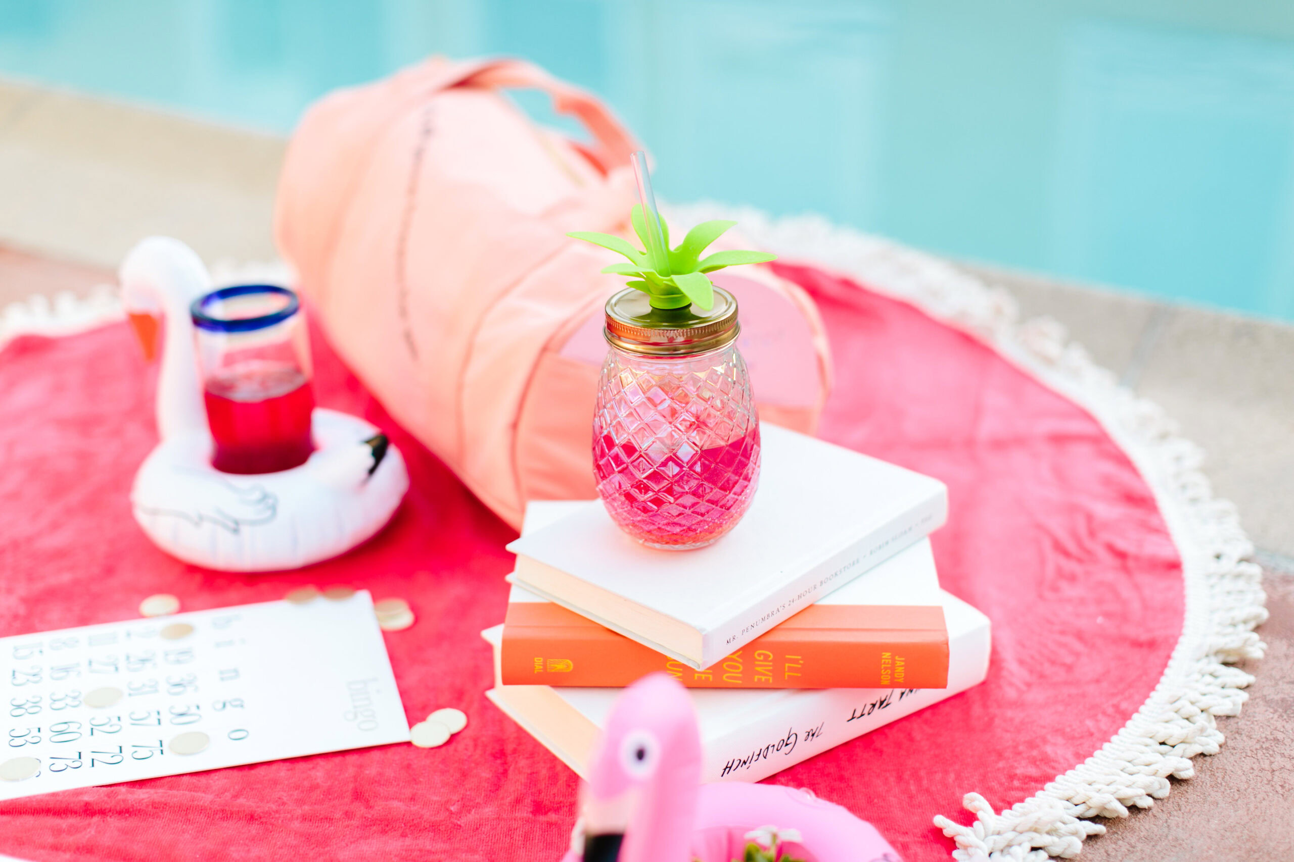 A pink towel with books, a drink in a jar, and inflatable pool floats is laid out by the pool—perfect for letting go and not stressing over what we can’t control.