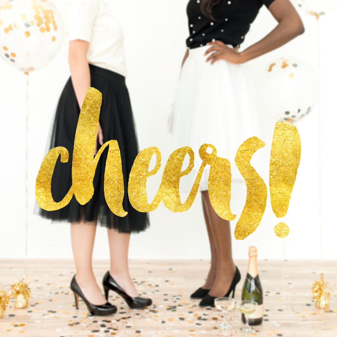 Two women in skirts stand near balloons and confetti, radiating joy. A gold "cheers!" text is overlaid, with a bottle and glasses in the foreground, capturing the holiday spirit.