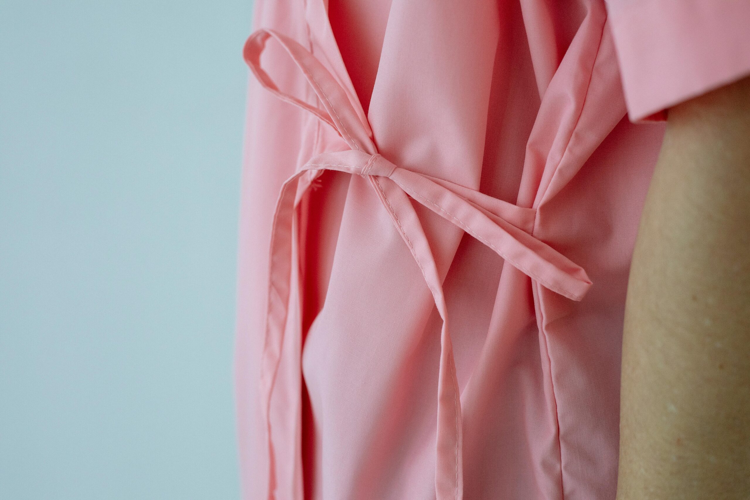 Close-up of a pink hospital gown with waist ties against a light background, symbolizing an integral part of health and wellness strategies.