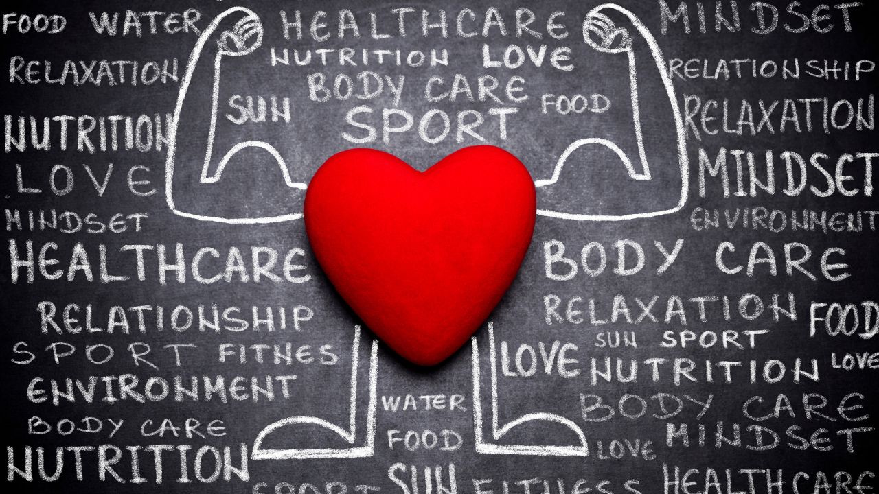 A red heart on a chalkboard displays words like "healthcare," "nutrition," and "mindset." Drawn muscular arms symbolize strength and well-being, highlighting women's heart health risks, particularly during menopause.