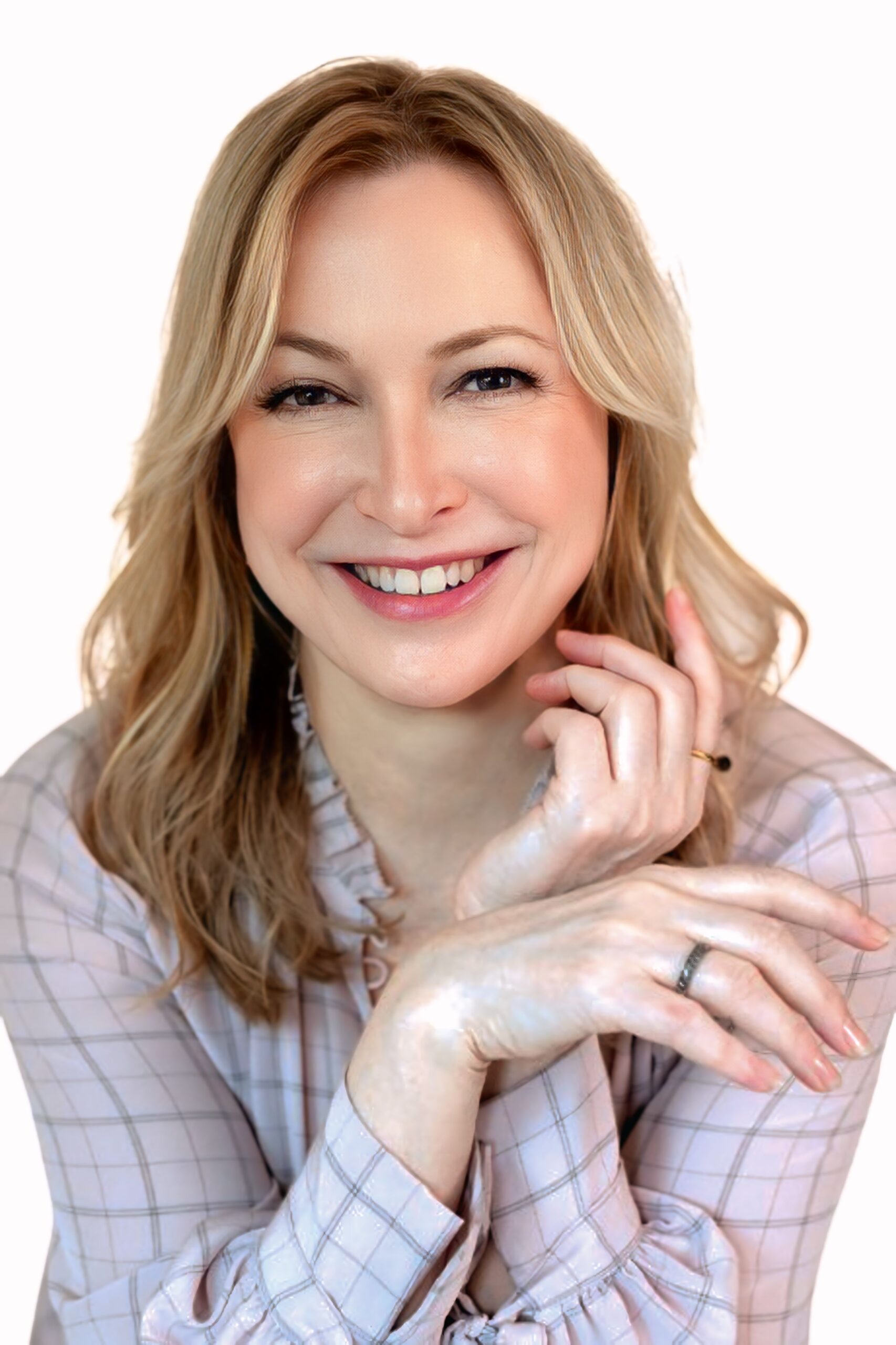 Erika Shershun, MA, MFT, with blonde hair and a plaid shirt smiles at the camera, hands resting in front of her, against a white background—embodying confidence in finding trauma-informed support.