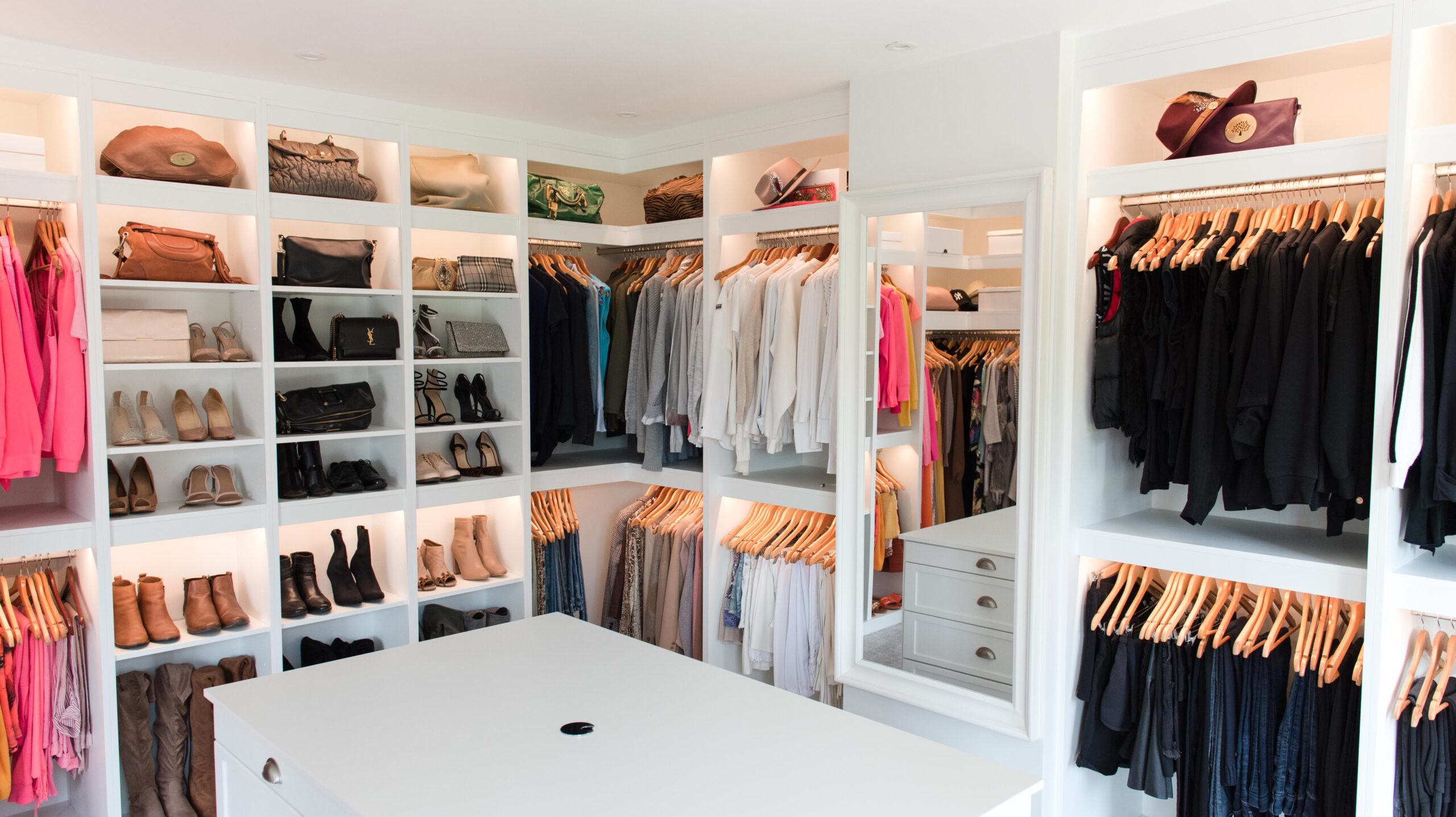 A neatly organized walk-in closet with shelves of shoes, bags, and folded clothes, plus hanging racks of shirts, jackets, and pants arranged by color—proof that even small changes can transform your life.